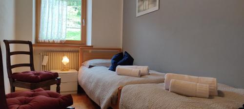 a bedroom with two beds and a chair and a window at Ai Grisi in Cavalese