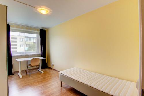 Cette chambre comprend un lit, un bureau et une fenêtre. dans l'établissement Savanorių av 48 Vilnius Students Home LT, à Vilnius