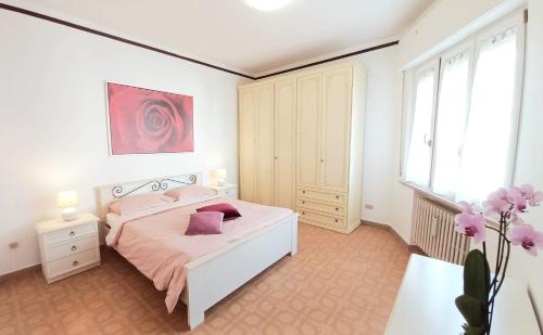 ein Schlafzimmer mit einem weißen Bett mit rosa Kissen in der Unterkunft Casa Nenetta a Mare in Civitanova Marche