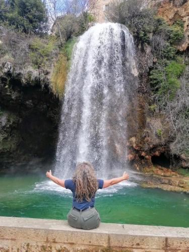 a woman sitting on a ledge in front of a waterfall at Le Temps Serein in Vabre-Tizac
