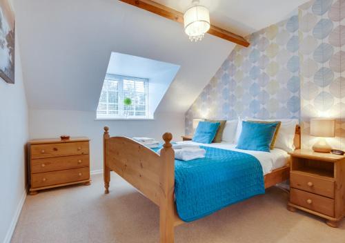 um quarto com uma cama com lençóis azuis e uma janela em Smugglers Cove Cottage em Ravenscar