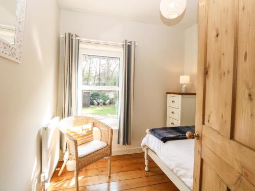 a bedroom with a bed and a window and a chair at 8 Melinda Cottage in Cromer