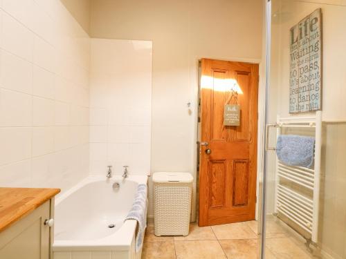 a bathroom with a white tub and a wooden door at 8 Melinda Cottage in Cromer