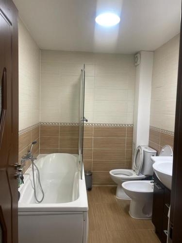 een badkamer met 2 toiletten, een bad en een wastafel bij Zimbrului Apartment in Bistriţa