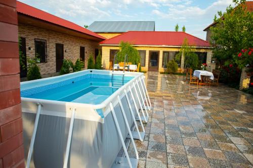 uma piscina num pátio com uma casa em Gostevoy Dom Гостевой Дом em Sheki