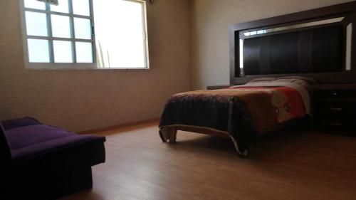 1 dormitorio con cama, ventana y sofá en AmpliaCasaconPrivacidad, en Toluca