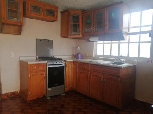 a kitchen with wooden cabinets and a stove top oven at AmpliaCasaconPrivacidad in Toluca