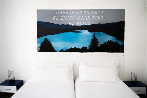 2 camas en una habitación con un cartel en la pared en Guest House Éxito en Madrid, en Madrid