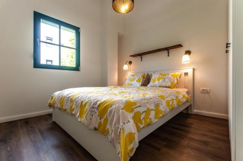 a bedroom with a bed with a yellow comforter and a window at Entire house in the center of Ljubljana - FREE PARKING - Dragon Garden Pavilion Ljubljana in Ljubljana