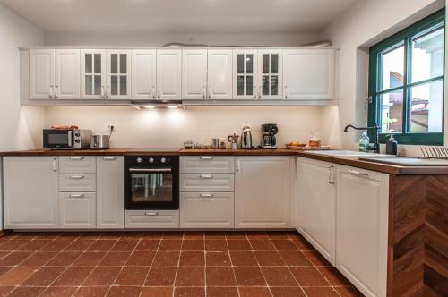 a kitchen with white cabinets and a brown tile floor at Entire house in the center of Ljubljana - FREE PARKING - Dragon Garden Pavilion Ljubljana in Ljubljana