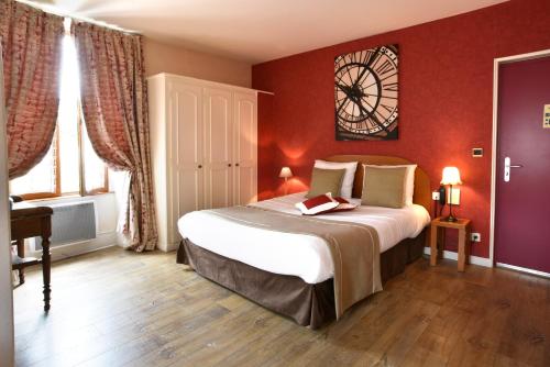 a bedroom with a large bed with a clock on the wall at Logis Hôtel-Restaurant Le Relais in Hauterives