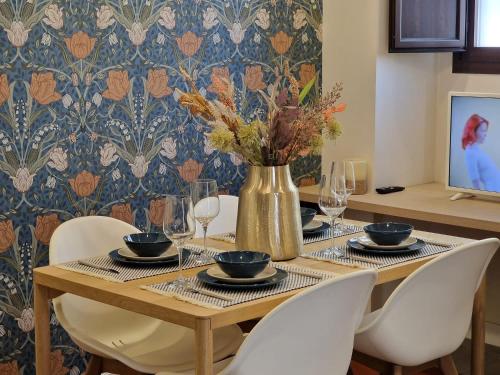 una mesa de comedor con sillas y un jarrón con flores en Triana Luxury Suite, en Sevilla
