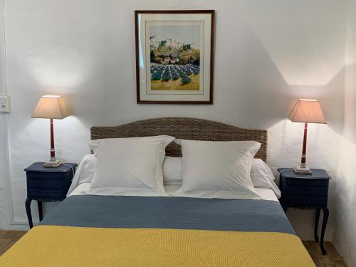 a bedroom with a bed with two lamps and a picture on the wall at L'Enclos du Micocoulier in Boissières