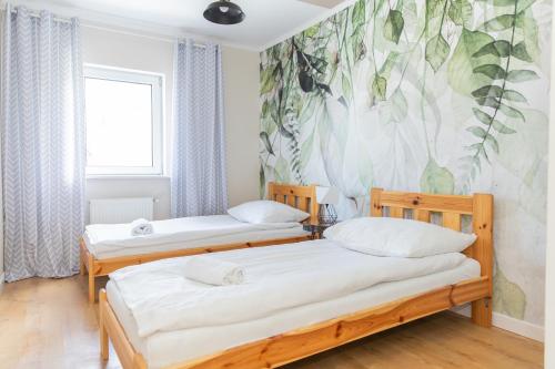 two beds in a room with a mural on the wall at Apartamenty Przylesie in Polanica-Zdrój