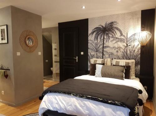 a bedroom with a large bed with a painting on the wall at Studio de charme avec jardin privatif à 10 minutes des plages in Le Beausset