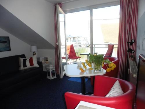 a room with red chairs and a table and a balcony at Yachthafenresidenz - Wohnung 6302 / 835 in Kühlungsborn