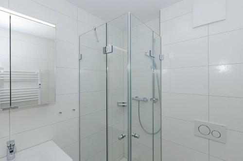 a glass shower in a bathroom with white tiles at Yachthafenresidenz-Wohnung-8403-908 in Kühlungsborn