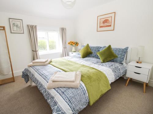 a bedroom with a bed with blue and green sheets and a window at Nash Cottage in Leominster