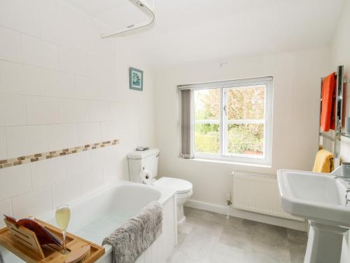 a white bathroom with a tub and a sink at Nash Cottage in Leominster