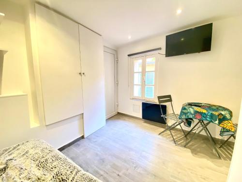 un salon avec une table et une télévision au mur dans l'établissement Mini Studio - Le Panisse By SCLS Locations, à Cannes