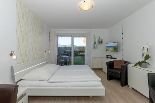 a white bedroom with a bed and a chair at Yachthafenresidenz-Wohnung-8105-9733 in Kühlungsborn