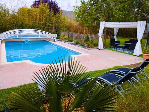 uma piscina num quintal com um gazebo em La maisonnette de Joséphine em Saint-Jean-des-Mauvrets