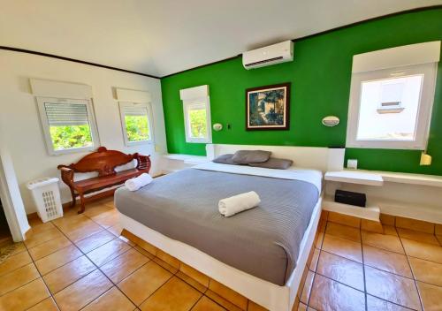 um quarto com paredes verdes e uma cama e uma cadeira em Las Veraneras Villas & Resort em Acajutla