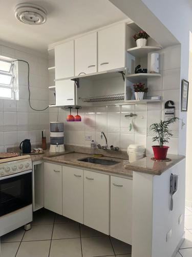 a white kitchen with white cabinets and a sink at Nosso apê no Guarujá - Unidade Aquário in Guarujá