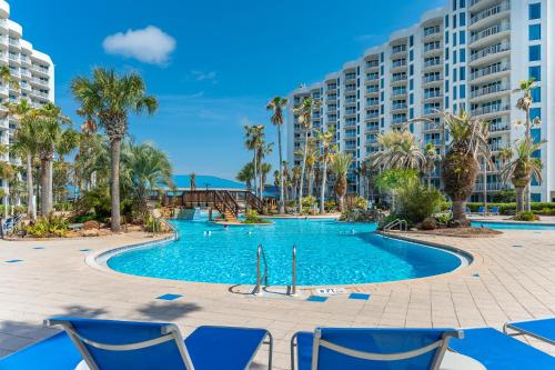 una piscina en el complejo con palmeras y sillas azules en Palms of Destin by Panhandle Getaways, en Destin