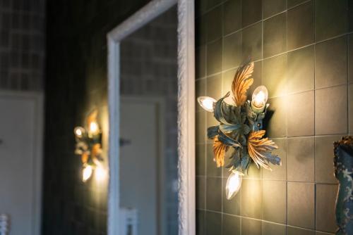 a flower decoration on a tiled wall next to a mirror at FORESTERIA di PALAZZO RADICI in Bergamo