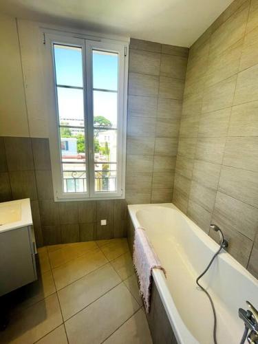 une salle de bain avec une baignoire et une fenêtre dans l'établissement SUPERBE 2 TERRASSES VUE MER, à Cannes