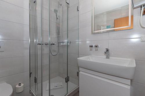 a white bathroom with a sink and a shower at Yachthafenresidenz-Wohnung-5304-816 in Kühlungsborn