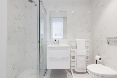 uma casa de banho branca com um lavatório e um chuveiro em Dragão - Indigo Antas Park no Porto
