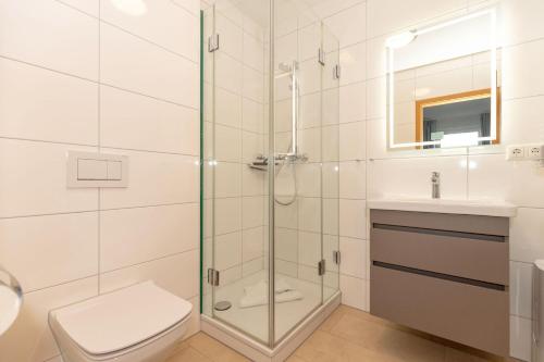 een badkamer met een douche, een toilet en een wastafel bij Yachthafenresidenz-Wohnung-6101-818 in Kühlungsborn