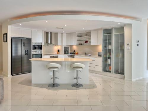 a kitchen with white cabinets and a large island with bar stools at Luxury resort style villa pool by Custom Bnb Hosting in Pelican Waters