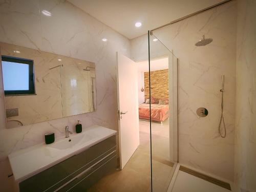 uma casa de banho com um lavatório e uma cabina de duche em vidro. em Villa Sunset na Guia