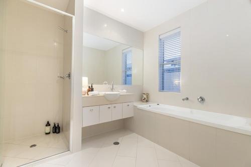 a white bathroom with a sink and a bath tub at Luxury resort style villa pool by Custom Bnb Hosting in Pelican Waters