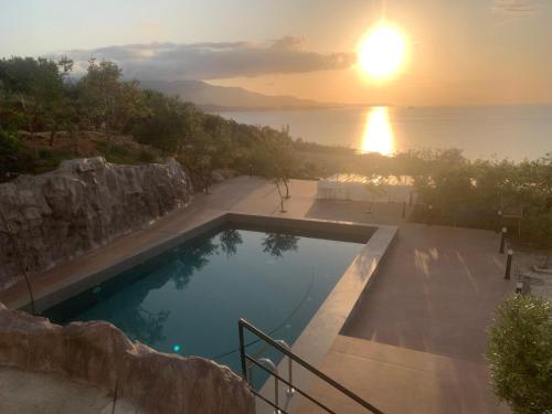 a swimming pool with a sunset in the background at Vila Bello in Ksamil