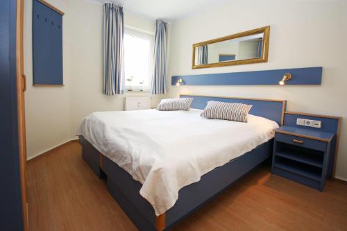 キュールングスボルンにあるYachthafenresidenz-Wohnung-8308-863のベッドルーム1室(青いヘッドボードと鏡付きのベッド1台付)