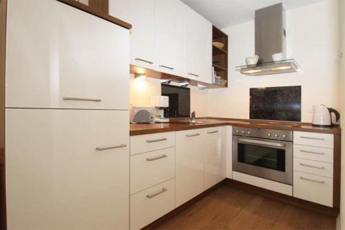 eine weiße Küche mit Holzböden und weißen Schränken in der Unterkunft Yachthafenresidenz - Wohnung 8312 / 864 in Kühlungsborn