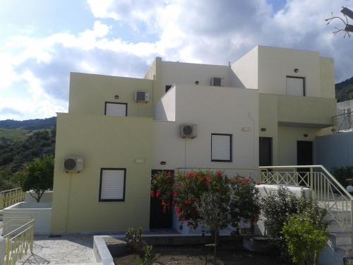 a large white house with trees in front of it at Polyrizos Hotel in Rodakino