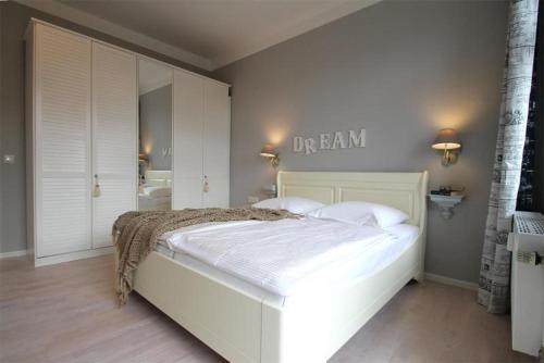 キュールングスボルンにあるResidenz-Ostseewind-Wohnung-15-9732の白いベッドが備わるベッドルームで、壁に看板が付いています。