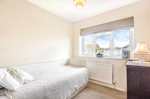 a white bedroom with a bed and a window at Pinellas Point in East Wittering