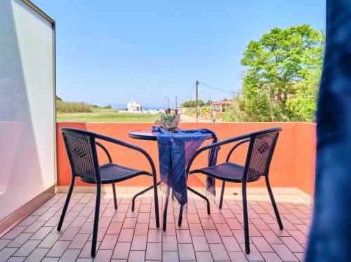 - une table et deux chaises sur la terrasse dans l'établissement Logas Beach Studios Peroulades Corfu, à Peroulades