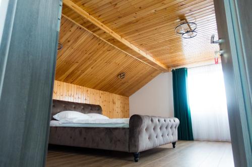 sypialnia z łóżkiem i drewnianym sufitem w obiekcie EDA ROOMS w Sybinie