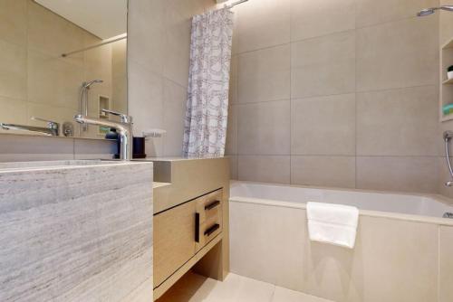 a bathroom with a tub and a sink and a shower at Address Beach Residence, JBR - Vacationer in Dubai