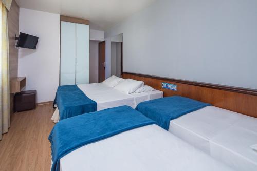 a hotel room with three beds and a television at Hotel Torre Sol in Balneário Camboriú