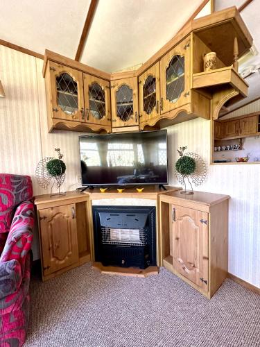 a room with wooden cabinets and a tv and a couch at Domek Holenderski Podlasie in Sejny