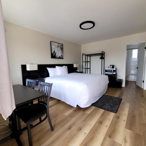 a bedroom with a white bed and a table and a desk at Richland Inn and Suites in Richland