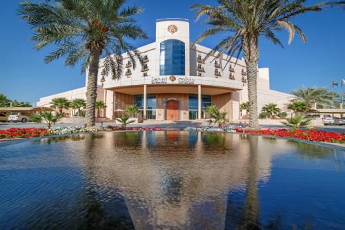a building with palm trees in front of a swimming pool at Danat Jebel Dhanna Resort in Jebel Dhanna